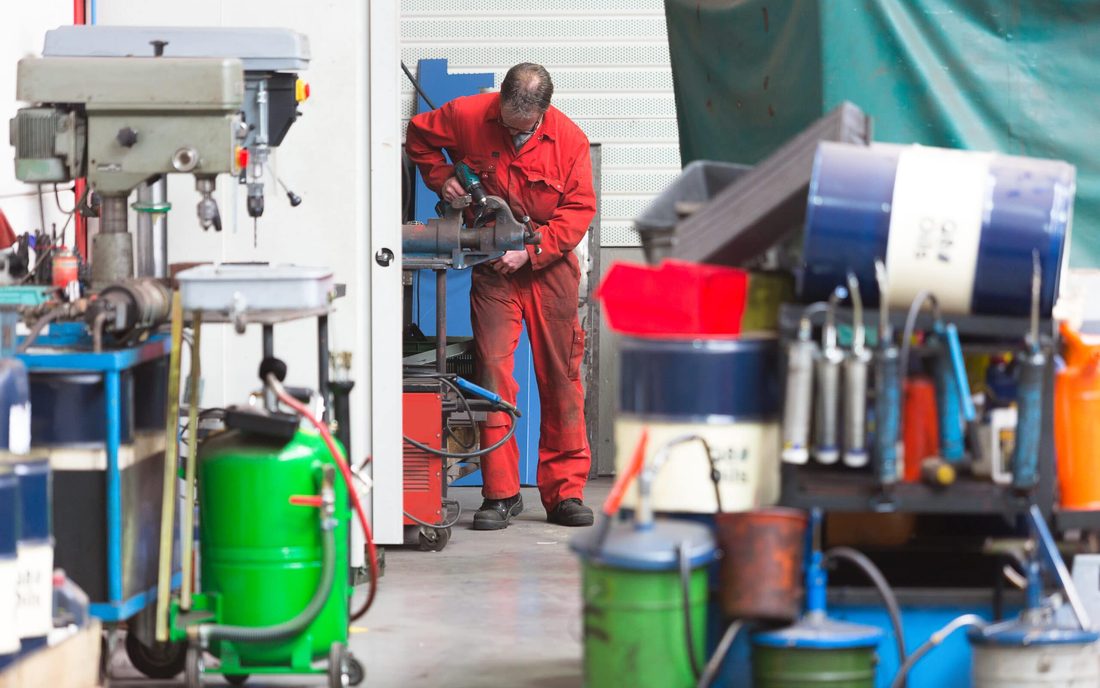 Técnico de mantenimiento trabajando junto a un taladro de columna en un taller industrial