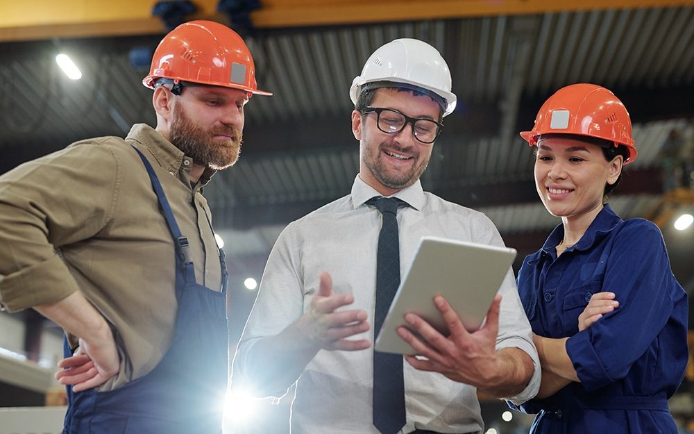 Jefe de mantenimiento repasa tareas con dos técnicos en la planta