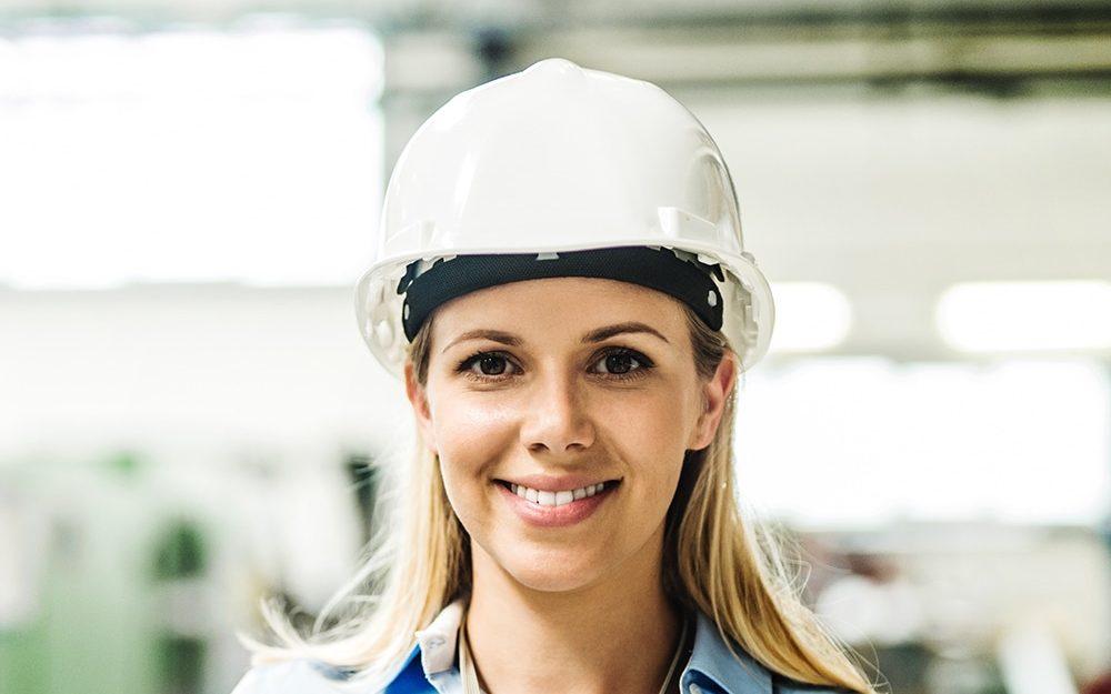 Ingeniera industrial con casco blanco en la línea de producción